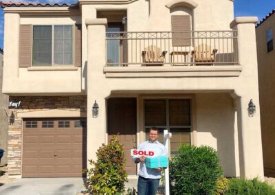 man holding a sold sign in front of house