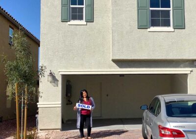 woman holding a sold sign in front of house