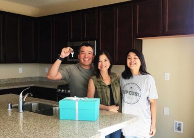 family of three holding the keys to their new house