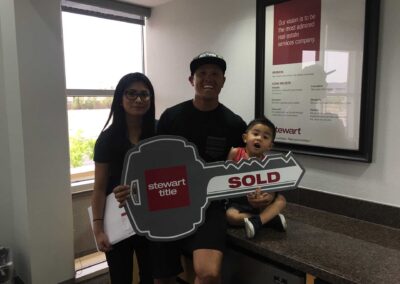 a family of three holding a huge key with the word sold
