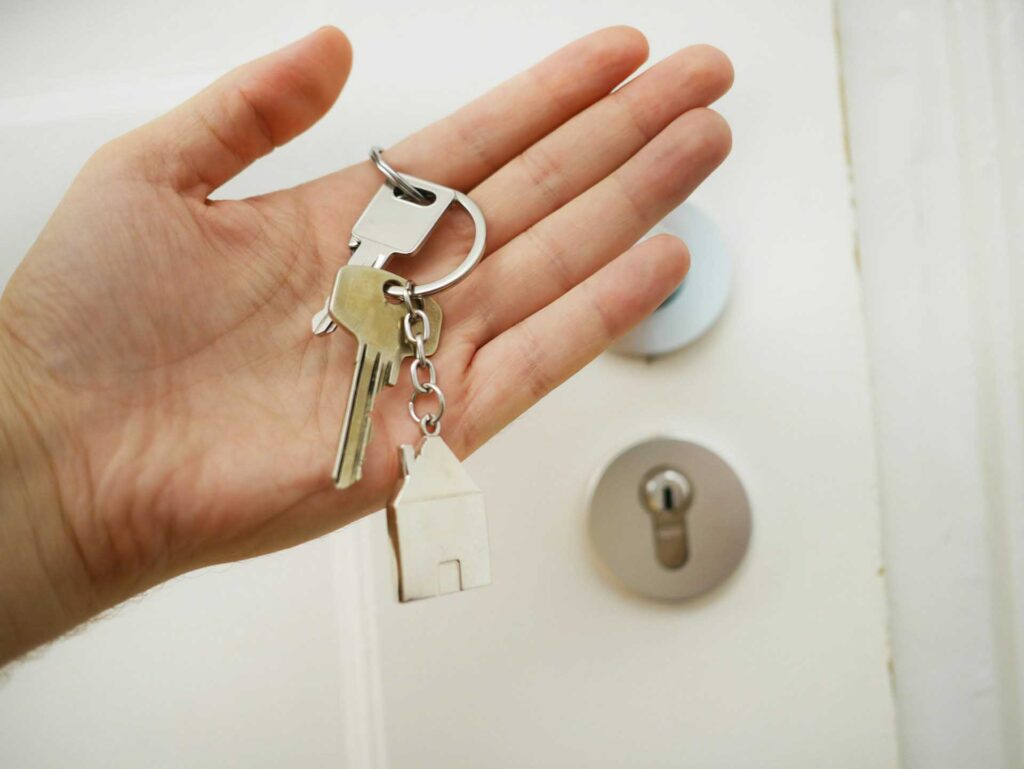 hand holding a set of keys in front of a door